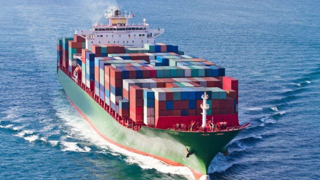 A large cargo ship filled with colorful containers sails on the ocean.