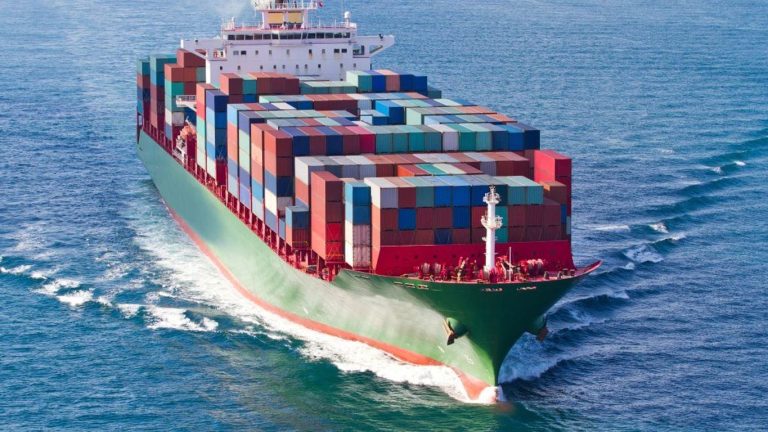 A large cargo ship filled with colorful containers sails on the ocean.