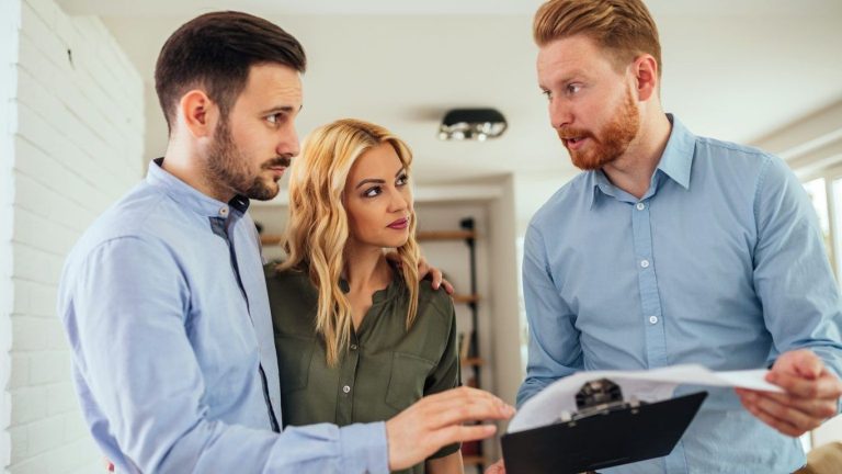 A person shows a document to a couple inside a room.